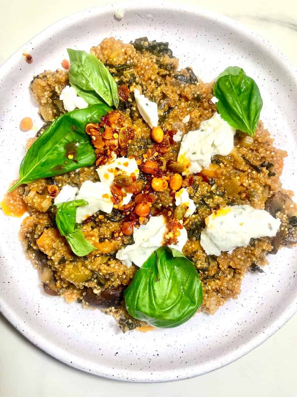 Vegan quinoa salad with fresh basil, roasted chickpeas, and creamy cheese crumbles for a healthy, plant-based meal.