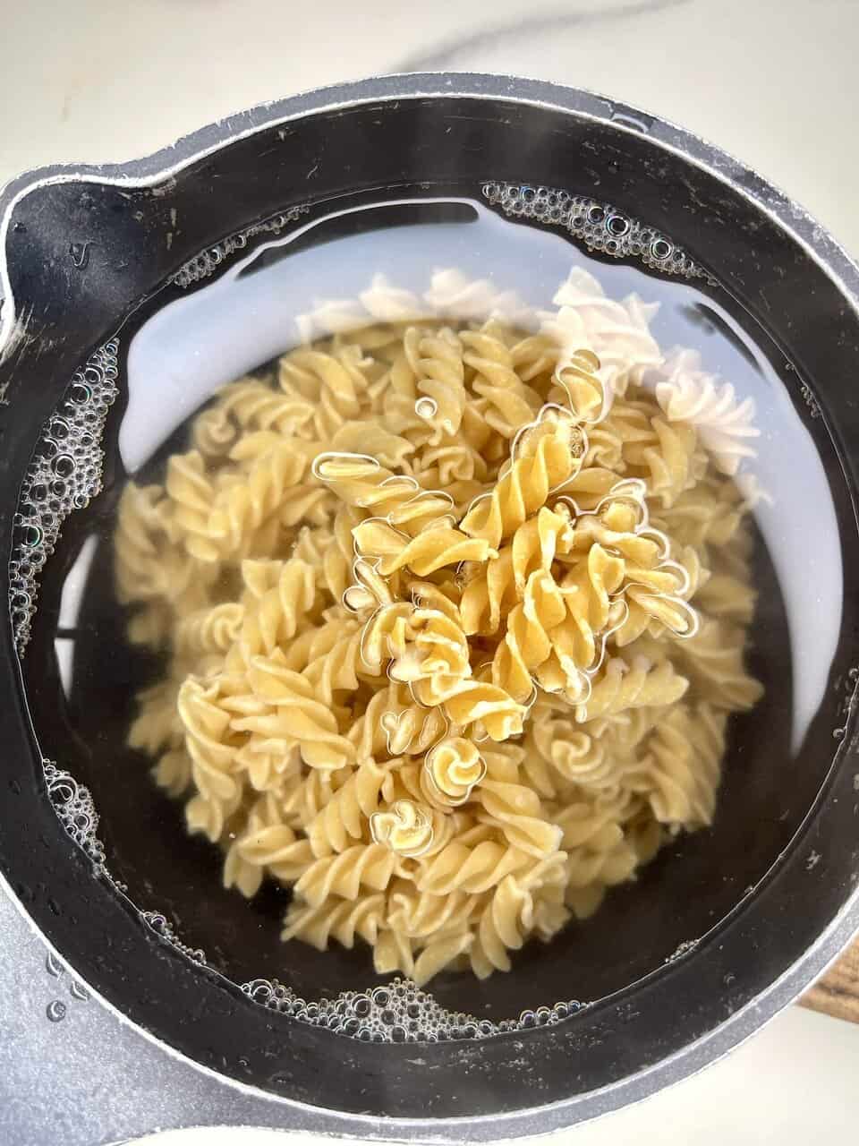 Bowl of vegan kids’ pasta with hidden vegetable sauce topped with fresh basil