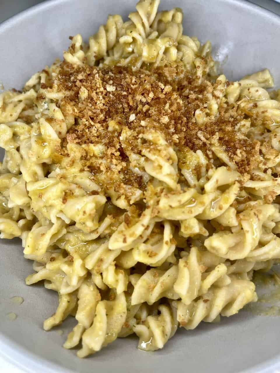 Bowl of vegan kids’ pasta with hidden vegetable sauce topped with fresh basil