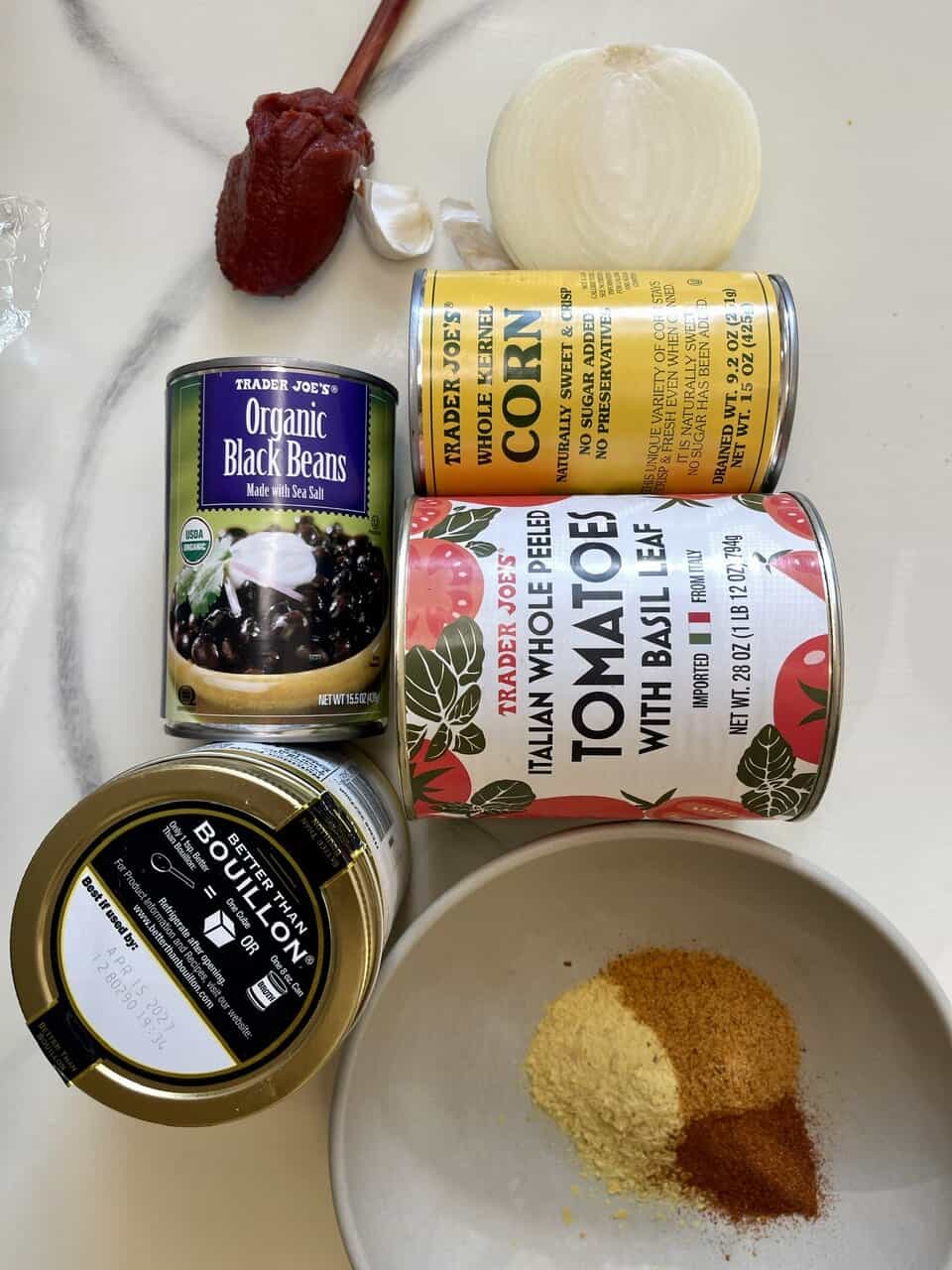 Earthy ingredients for wholesome cooking, including black beans, canned tomatoes, vegetable bouillon, onion, and spices.