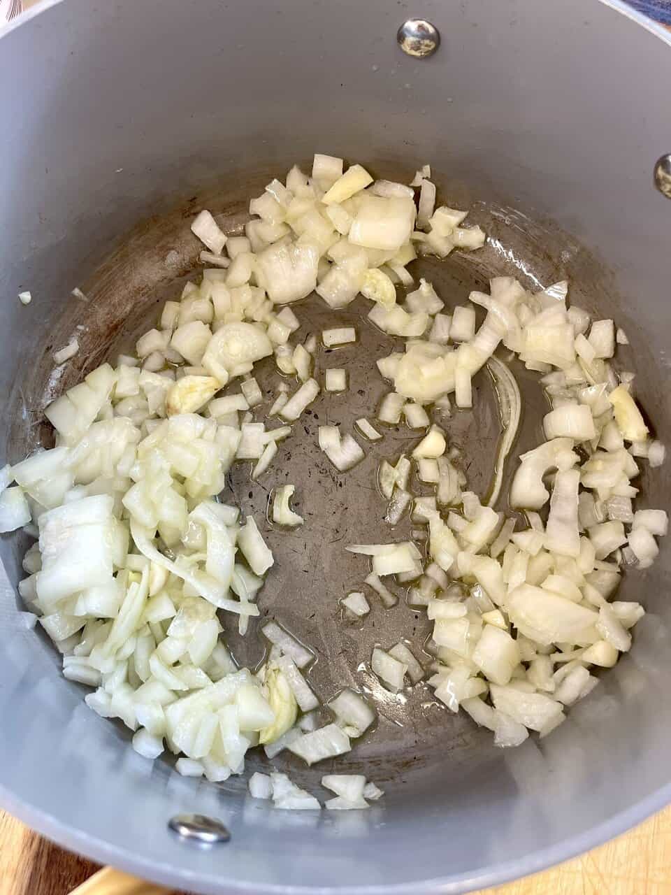 Sautéing diced onions in a stainless steel pan for healthy cooking.