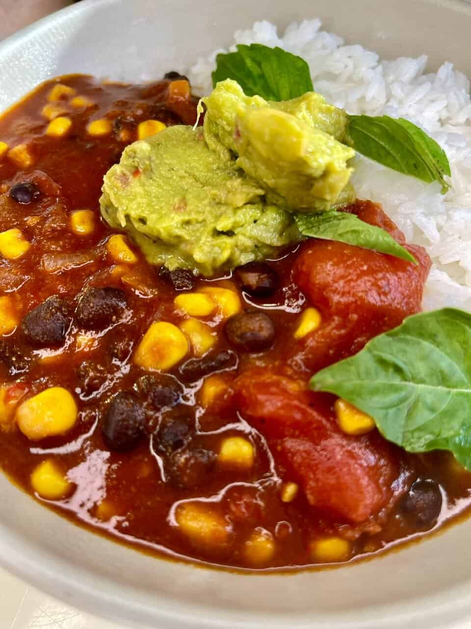 Creamy avocado and rice with chili beans and fresh basil garnish.
