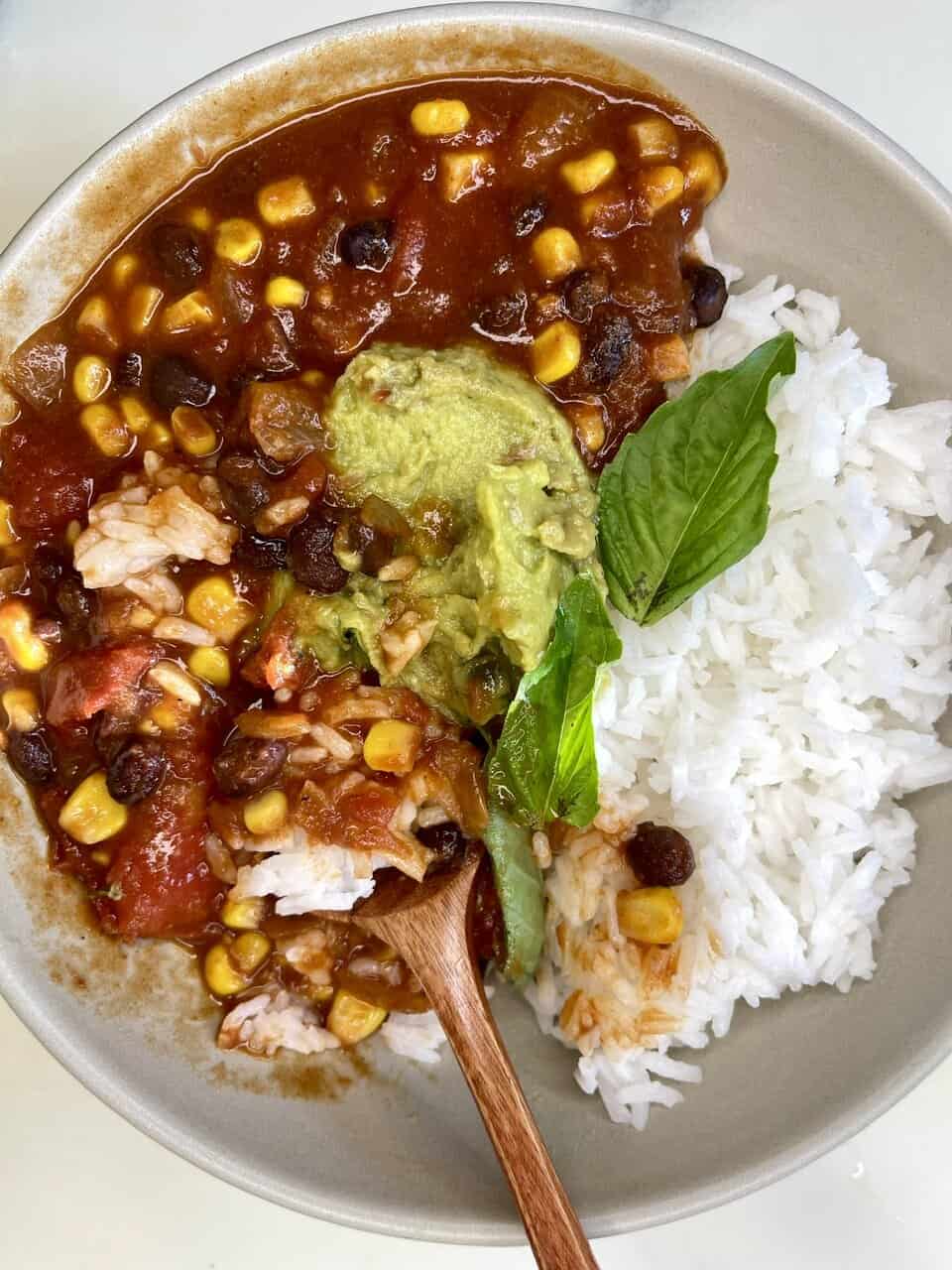 Steak and veggie chili served with white rice, topped with fresh basil and avocado. Healthy, hearty, and flavorful meal.