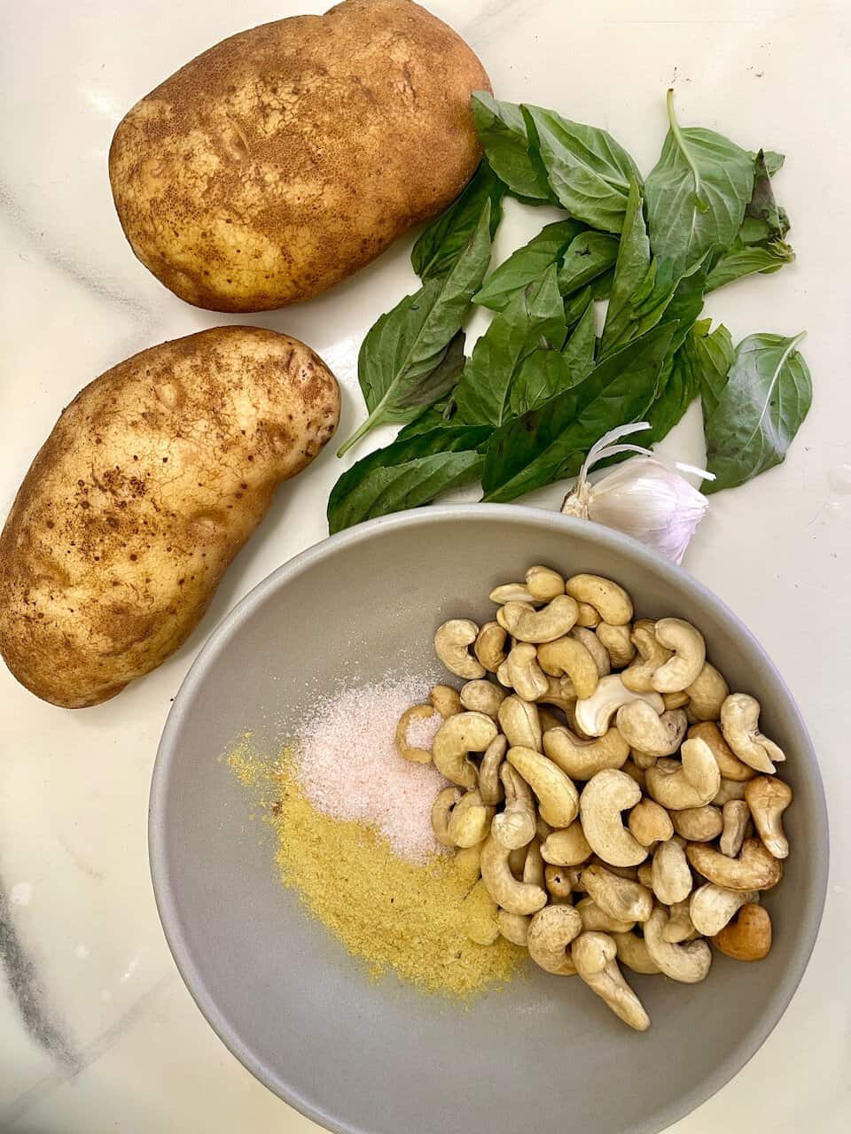 Organic potatoes, fresh basil, garlic, cashew nuts, and natural seasonings for healthy, plant-based recipes.