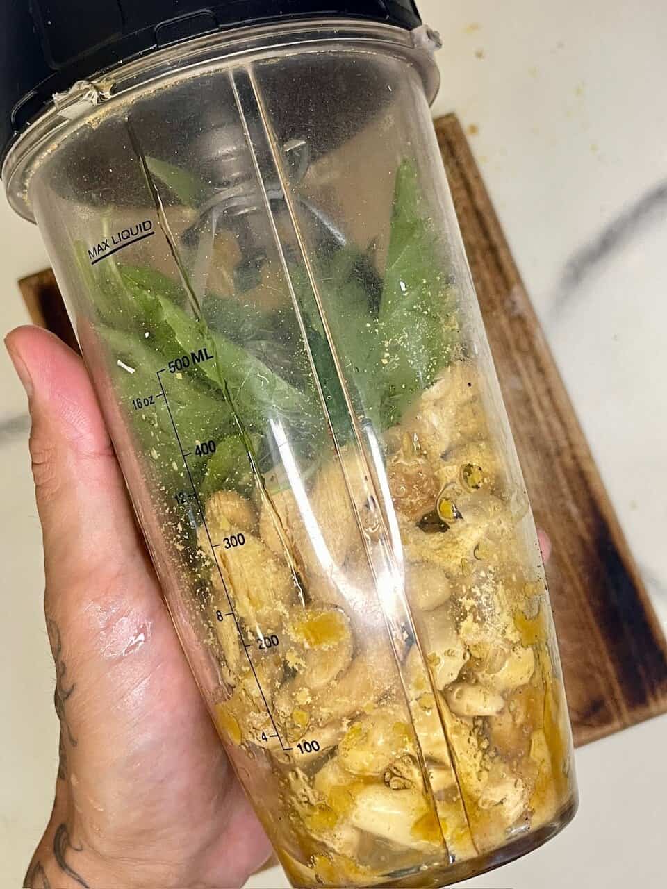 Blended herbal tea ingredients in a blender with mint leaves, ginger, and other natural components.