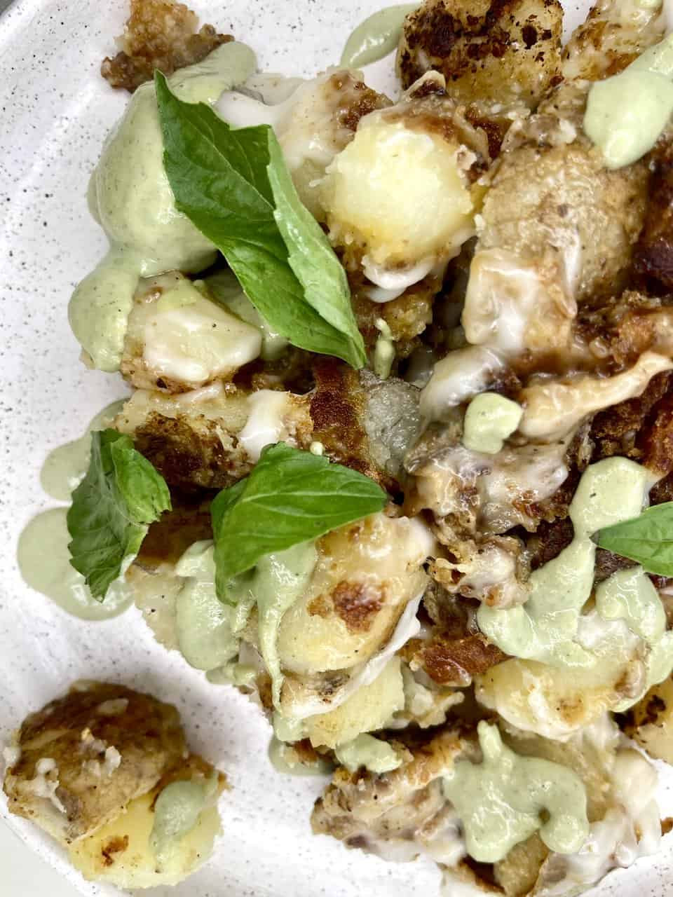 Creamy cauliflower cheese bites with fresh basil and herb drizzle, perfect for healthy, flavorful meals.