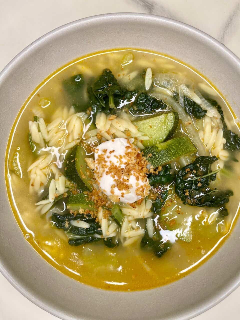 Fresh vegetable soup with orzo, topped with sour cream and crushed croutons, promoting wholesome, healthy eating.