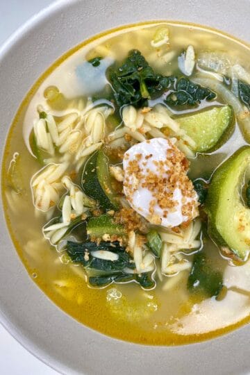Fresh veggie noodle soup with herbs, lime, and garnish, promoting healthy living and mindful eating.