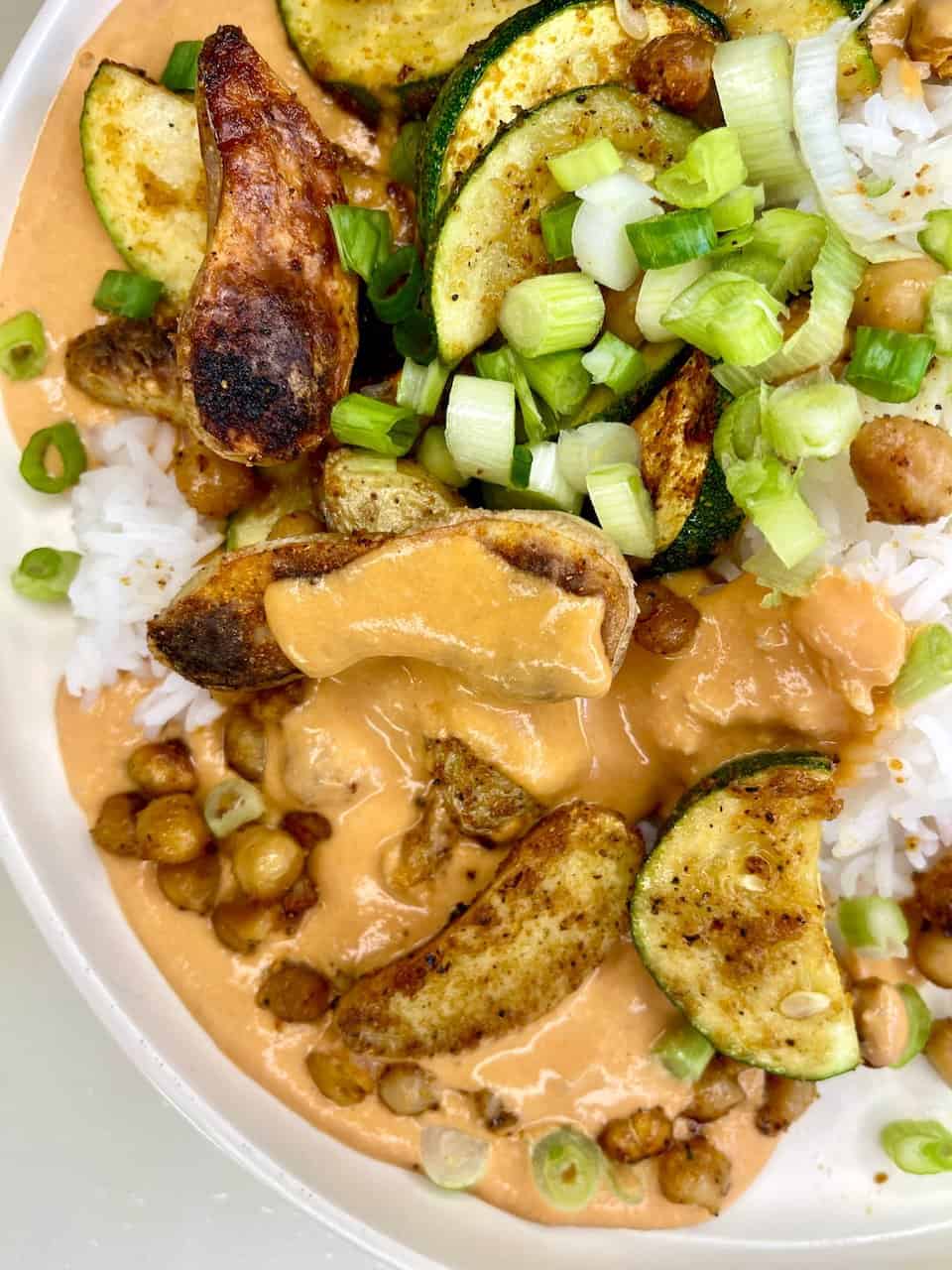 Fresh grilled zucchini and roasted eggplant with green onions on white rice, drizzled with creamy peanut sauce.