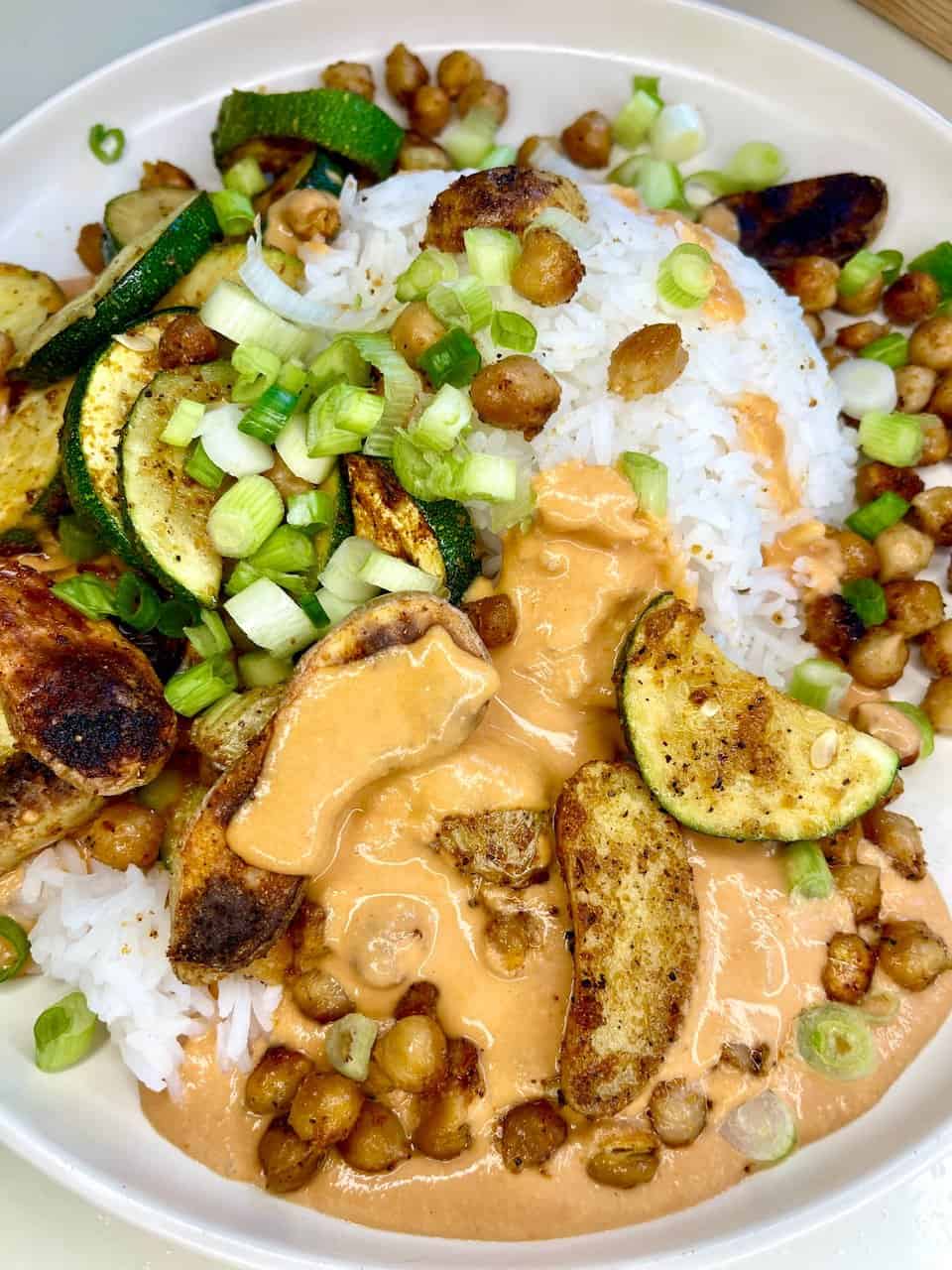 Grilled zucchini, roasted cauliflower, and chickpeas with rice and creamy peanut sauce. Healthy vegan meal for body and soul.
