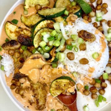 Savory vegan chickpea curry with roasted zucchini and rice, topped with green onions.