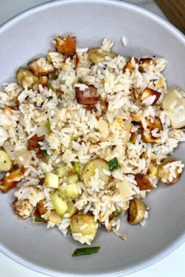 Savory fried rice with chicken, vegetables, and herbs in a light gray bowl.