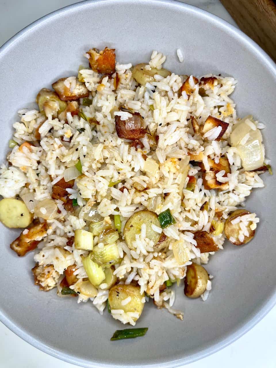 Savory fried rice with chicken, vegetables, and herbs in a light gray bowl.