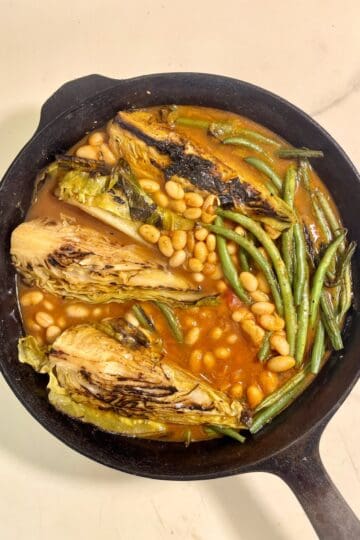Braised hispi cabbage with green beans and white beans in a rich tomato miso broth.