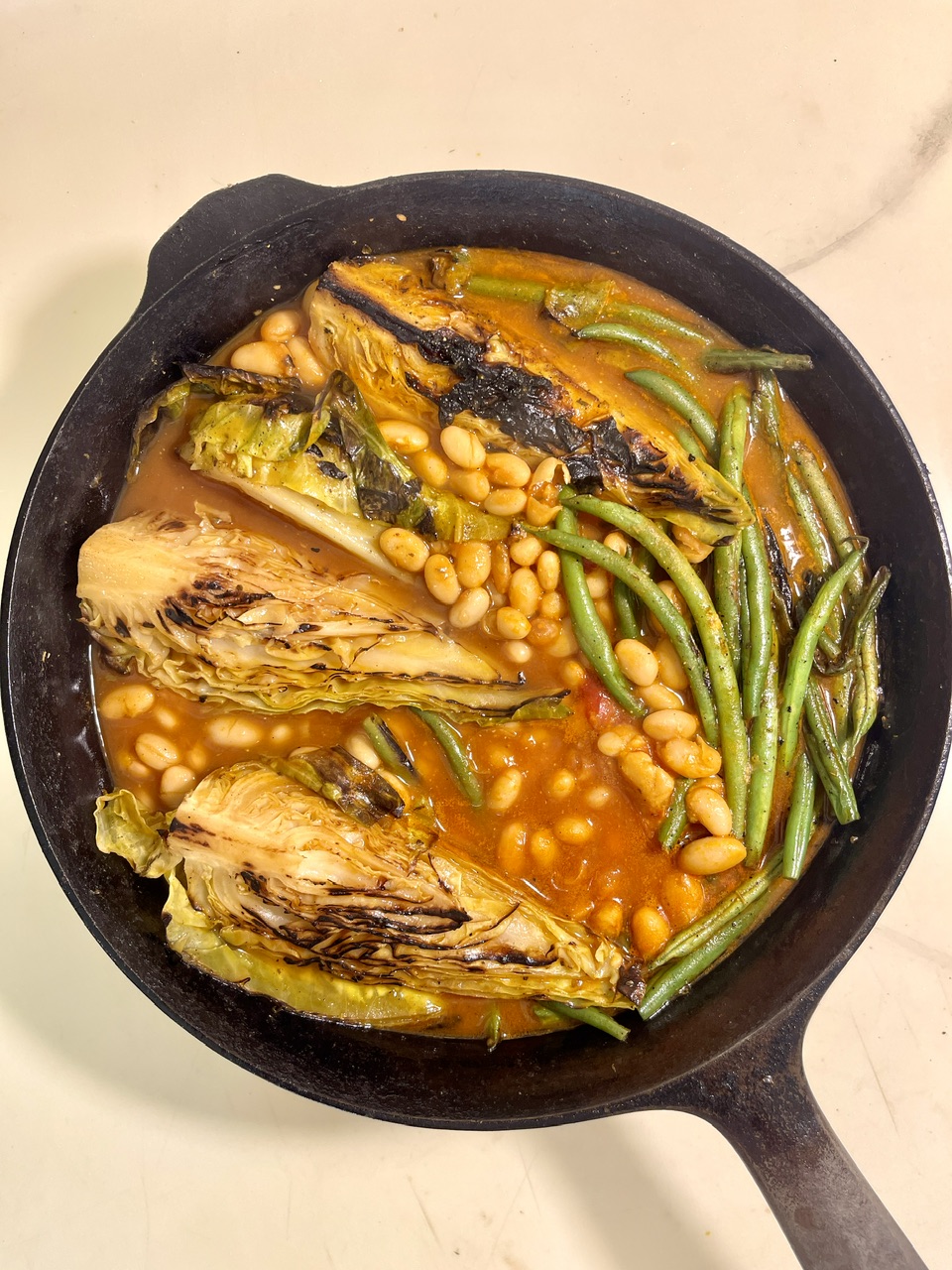 Braised hispi cabbage with green beans and white beans in a rich tomato miso broth.
