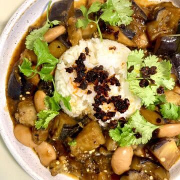 Caramelized eggplant with beans and rice, garnished with cilantro.