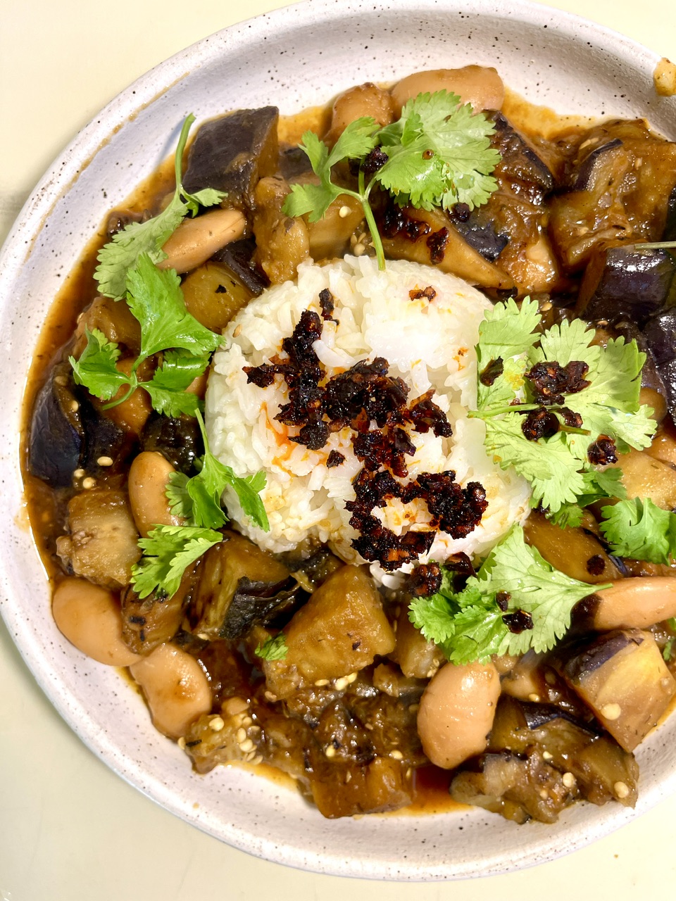 Caramelized eggplant with beans and rice, garnished with cilantro.
