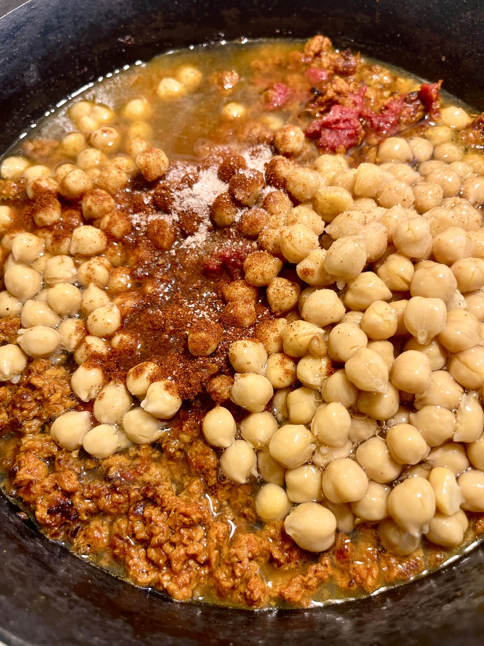 Chickpeas in a skillet with spice and oil, vegan chorizo flavors.