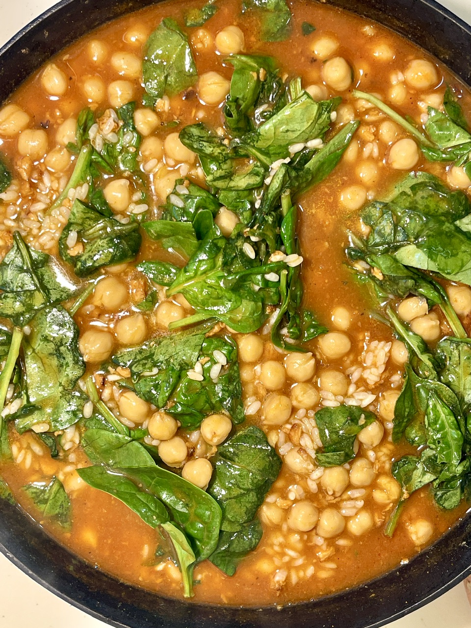 Chickpea and spinach hearty stew in orange tomato sauce with sesame.