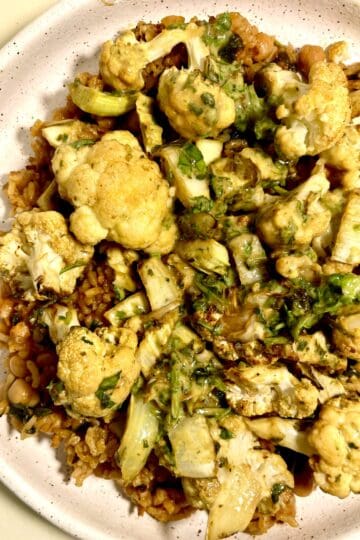 Curry cauliflower and chickpea chorizo over seasoned rice in a bowl.