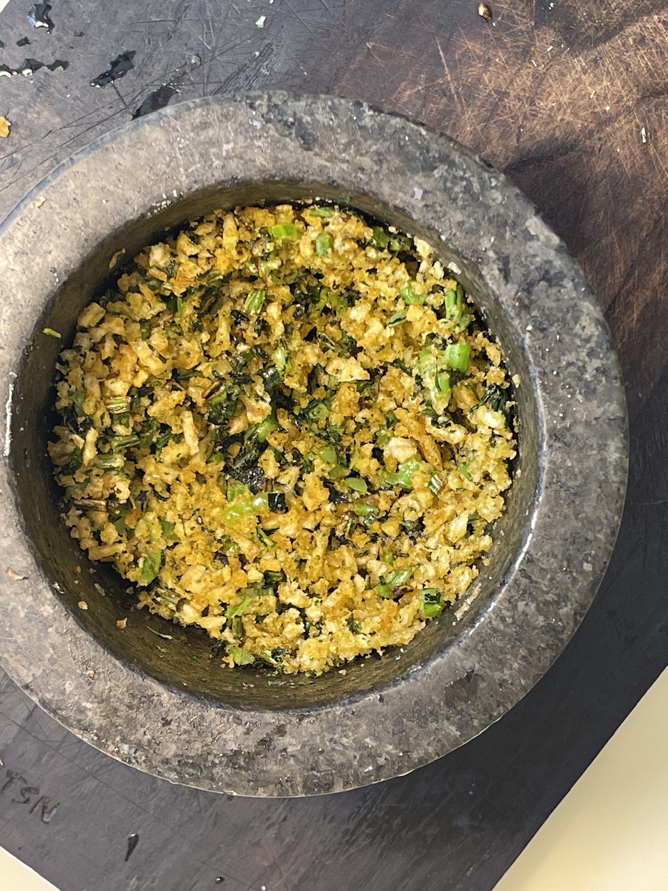 Golden roasted butternut squash and white beans crumble with green herbs in a stone bowl.