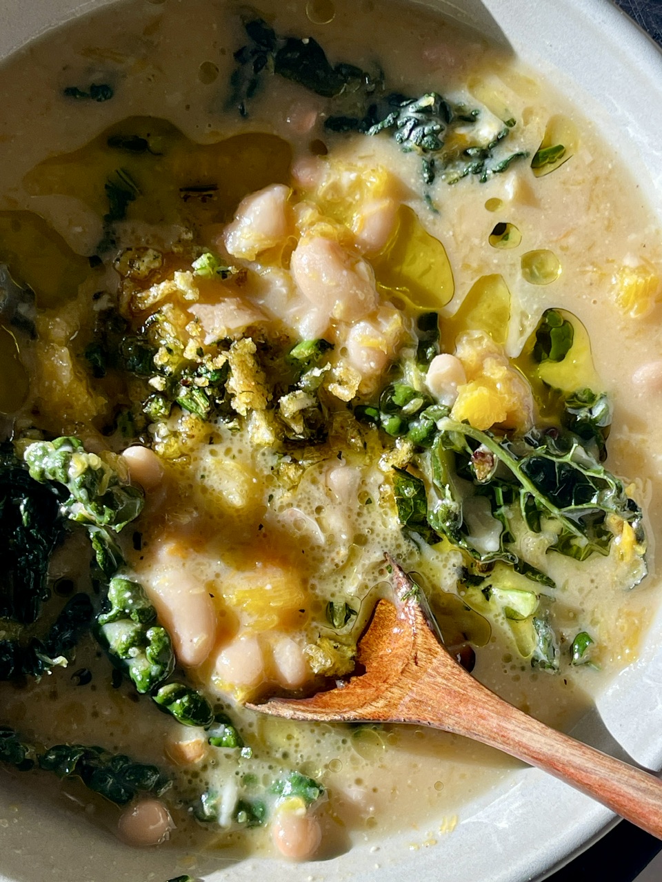 Creamy white bean and kale stew with coconut-miso notes in a bowl.