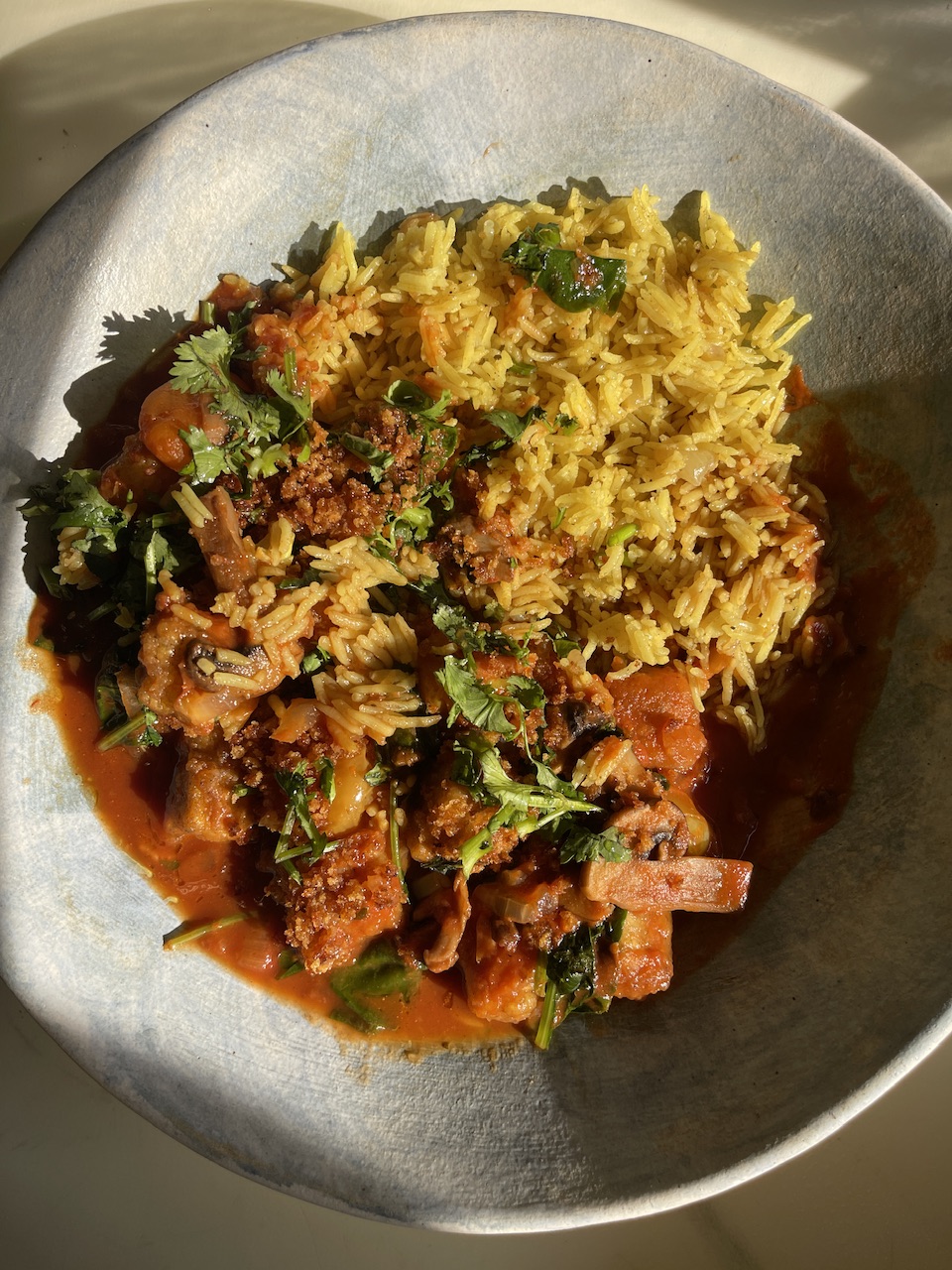 Vegan biryani with crispy tofu and fresh herbs in a bowl.