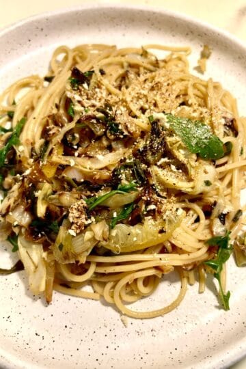 Close-up of caramelized cabbage spaghetti with lemon and herbs on a white plate.