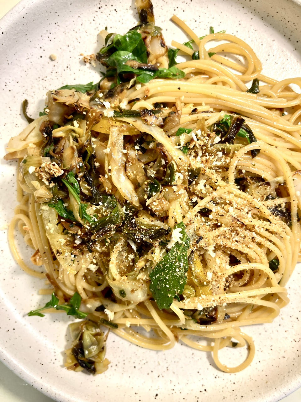 Delicious caramelized cabbage spaghetti with lemon and arugula on a white plate.