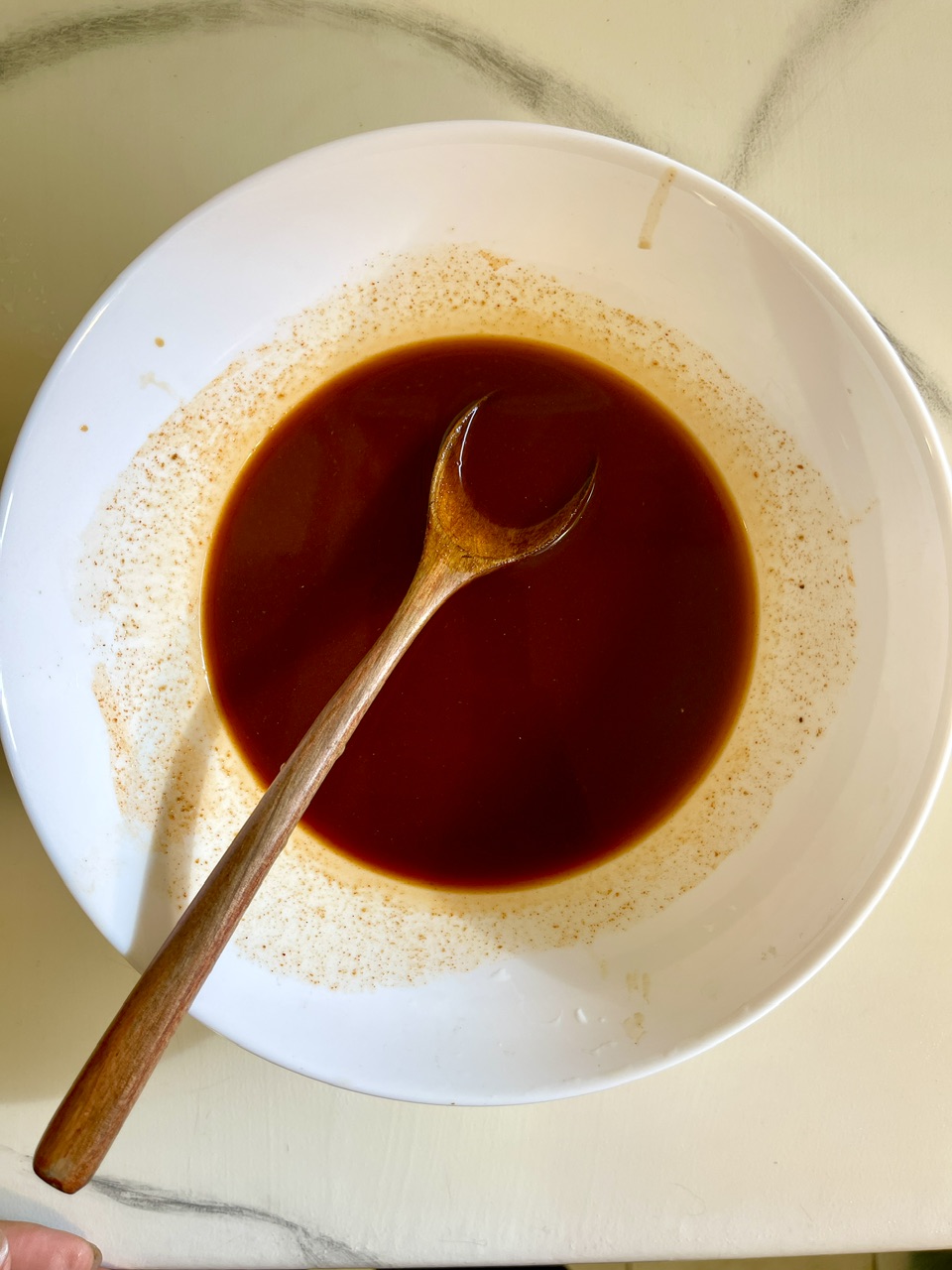 Close-up of a bowl of vegan unagi sauce with a wooden spoon.