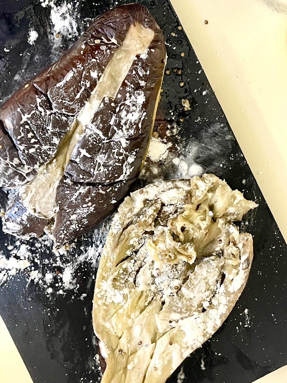 Raw eggplant being prepared for vegan unagi dish on black surface.