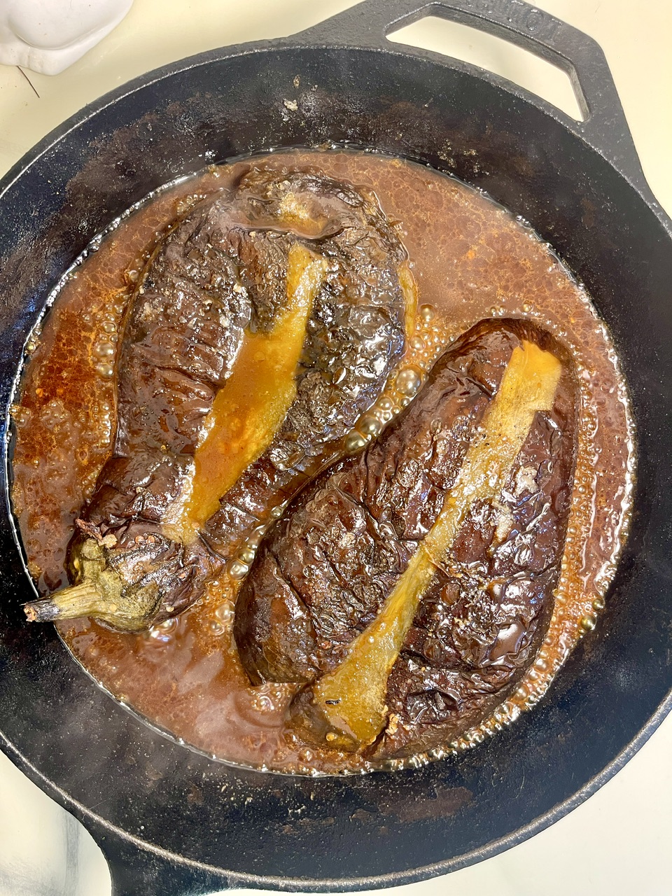Vegan eggplant unagi cooking in a skillet with sauce.