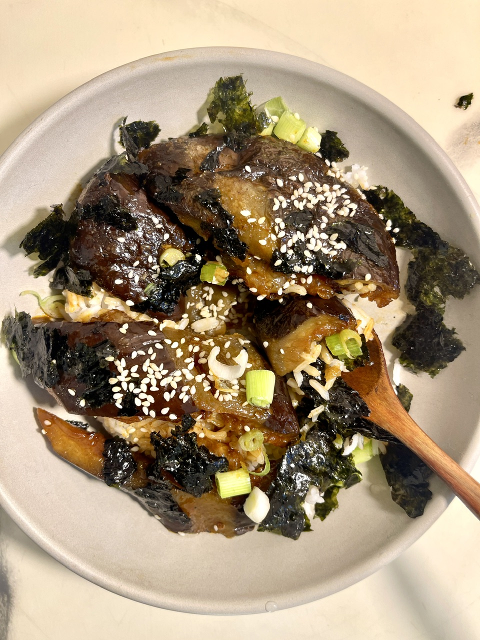 Vegan eggplant unagi with seaweed and green onions on a plate.