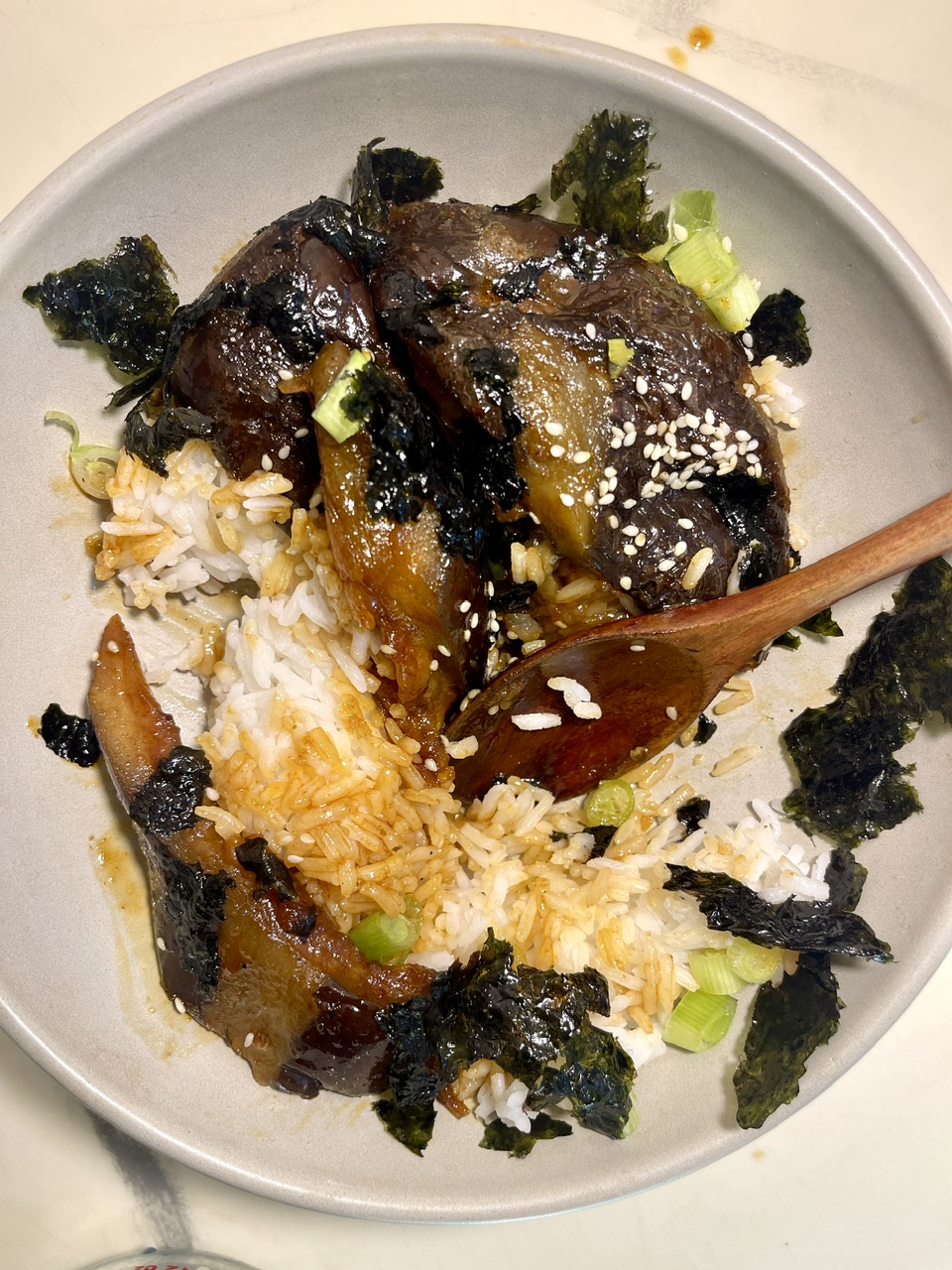Vegan eggplant unagi served over rice with seaweed and sesame seeds.