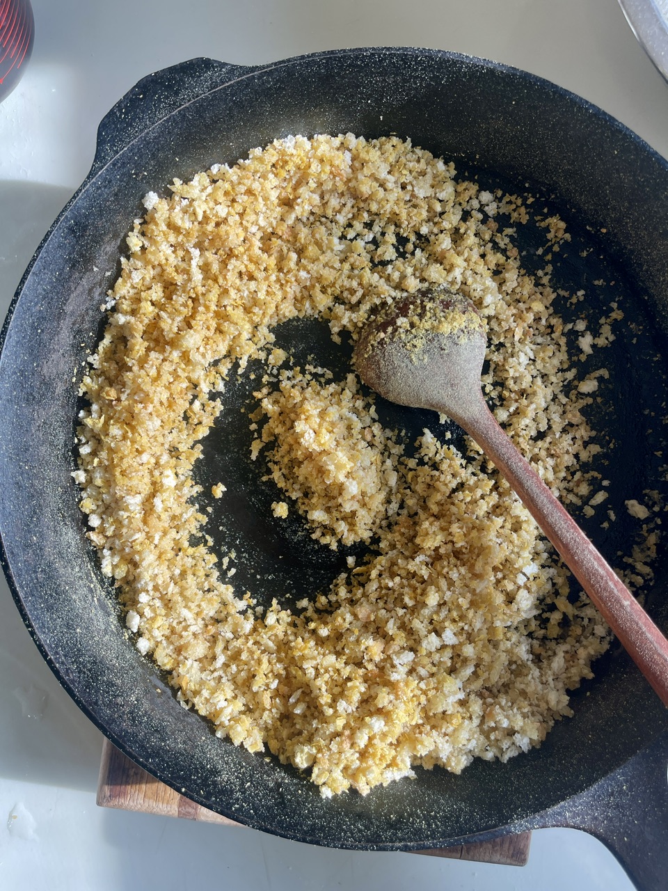 Cooking vegan garlic linguine with crispy vegan bacon in a skillet.