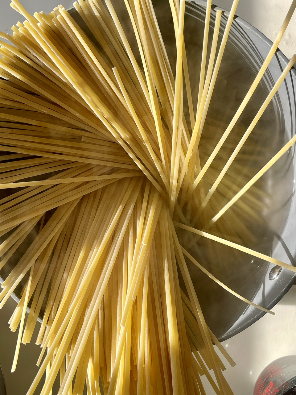 Raw vegan spaghetti pasta soaking in water for cooking or preparation.