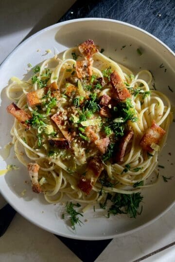 Vegan garlic linguine with crispy vegan bacon and fresh herbs.