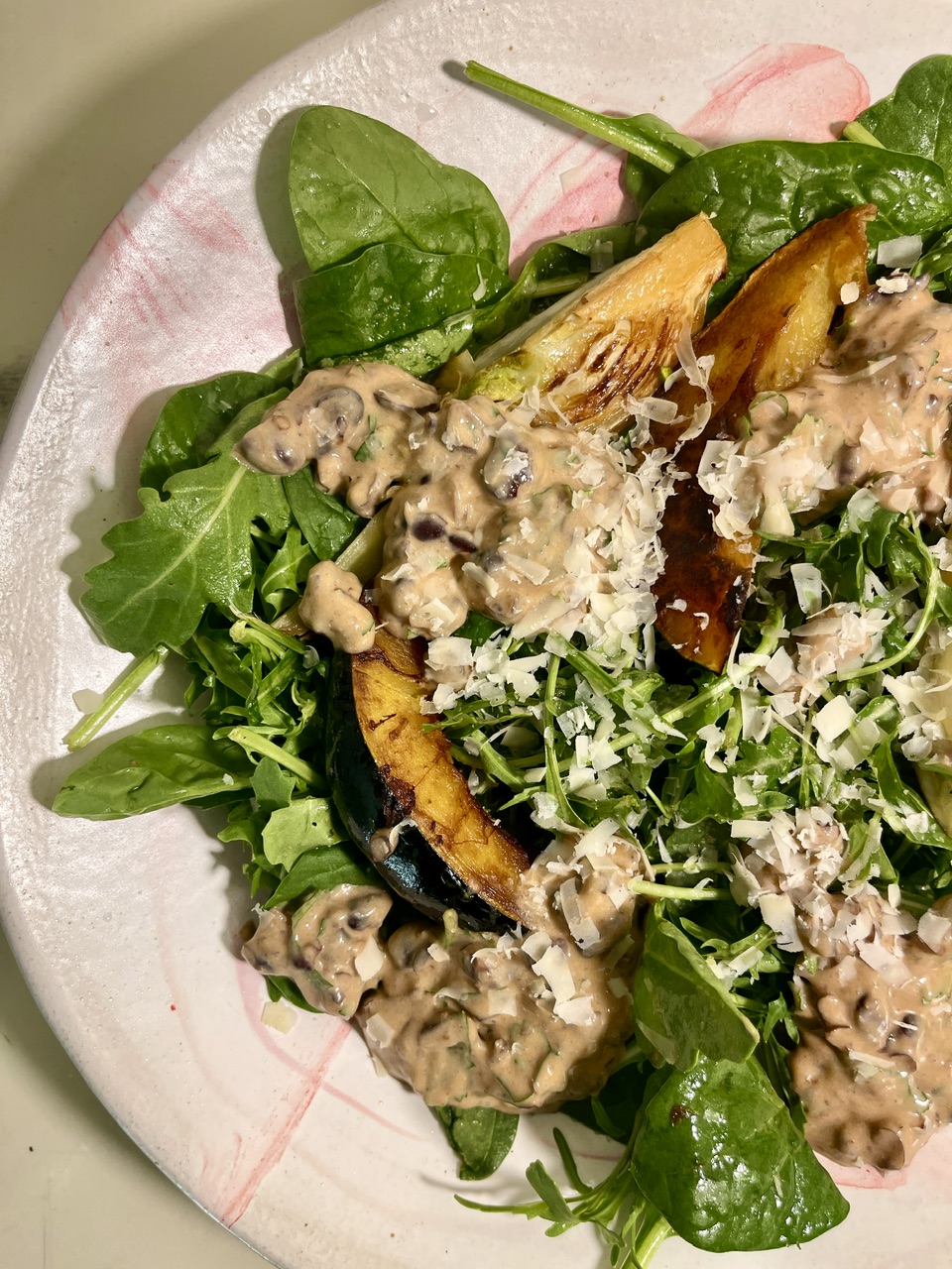 Fresh vegan yogurt bean salad with seared vegetables and greens on a white plate.