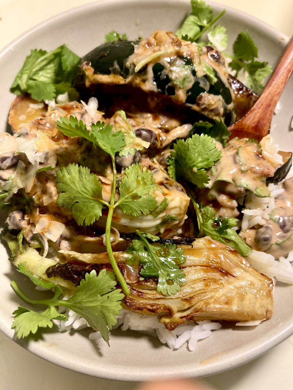 Vegan yogurt beans with seared vegetables and cilantro on rice.
